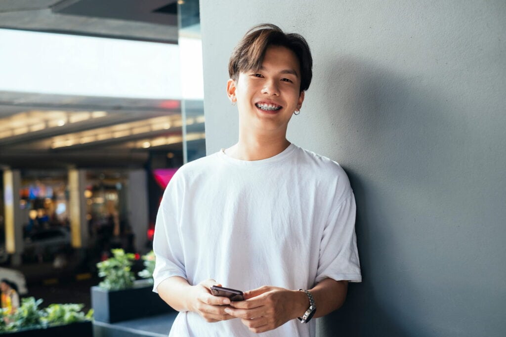 A teenager in a white shirt with braces shows off his smile.